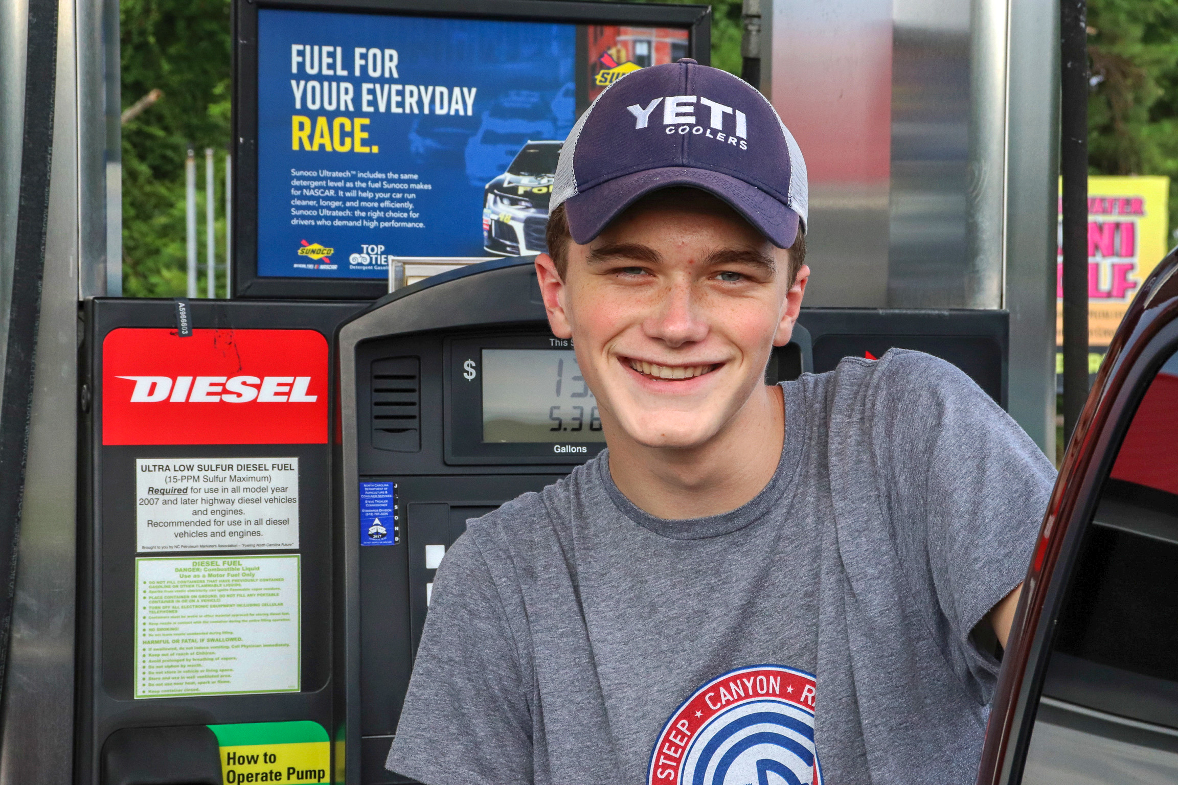 Young man pumping gas at his car